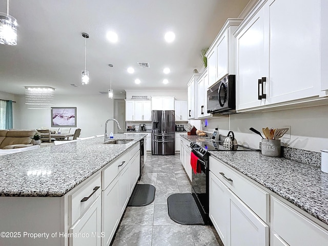 kitchen with a center island with sink, white cabinets, hanging light fixtures, black appliances, and a sink