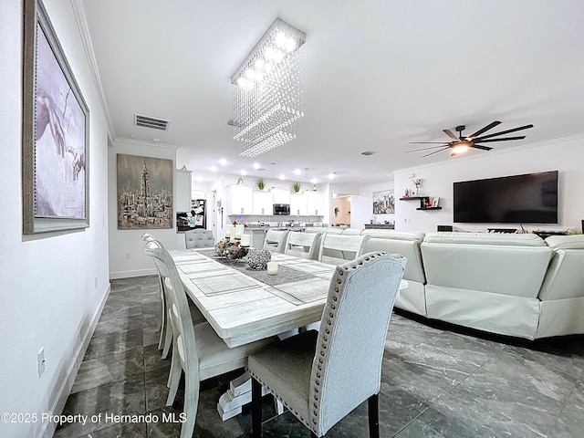 dining room with ceiling fan with notable chandelier, ornamental molding, visible vents, and baseboards