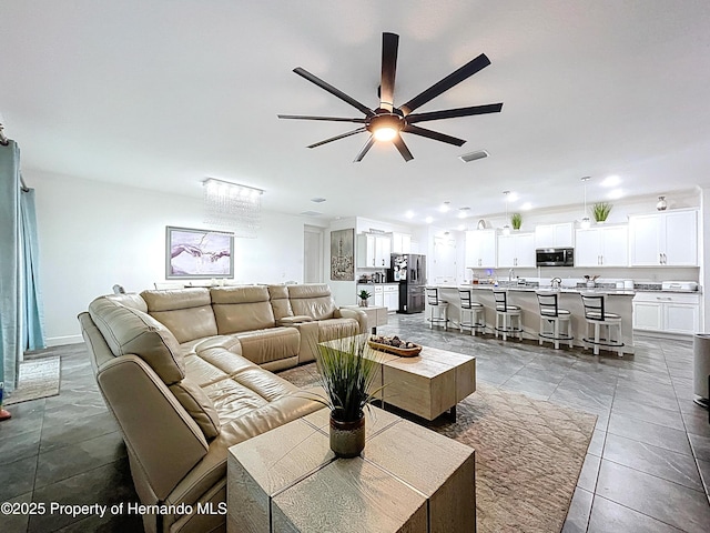 living area with tile patterned flooring, visible vents, and a ceiling fan