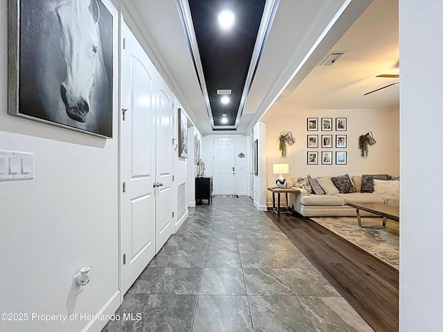 hall with ornamental molding, dark wood-style flooring, visible vents, and baseboards