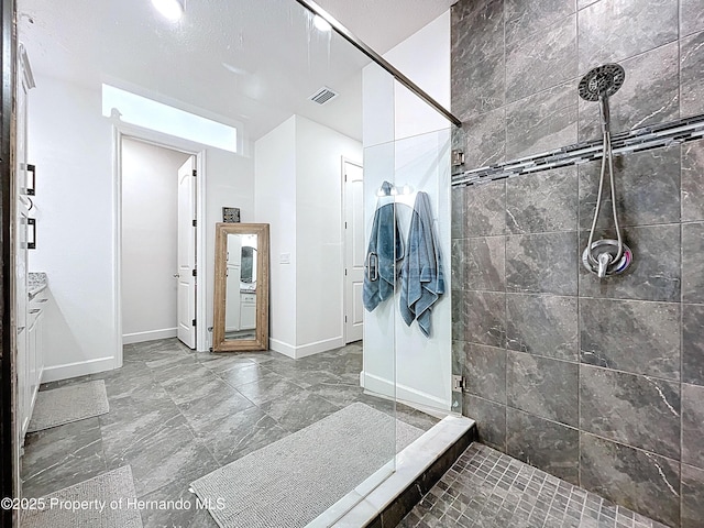 full bath featuring baseboards, visible vents, and a tile shower