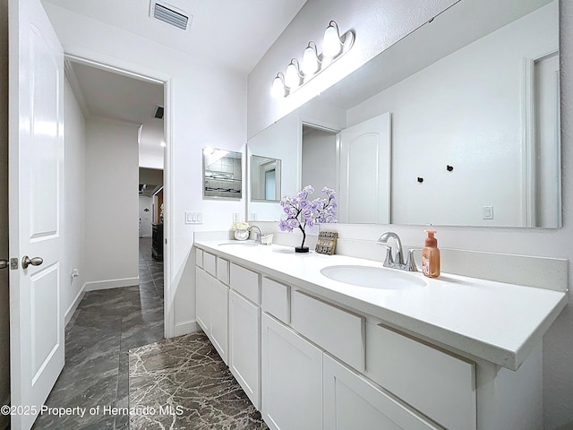 bathroom featuring visible vents, a sink, baseboards, and double vanity