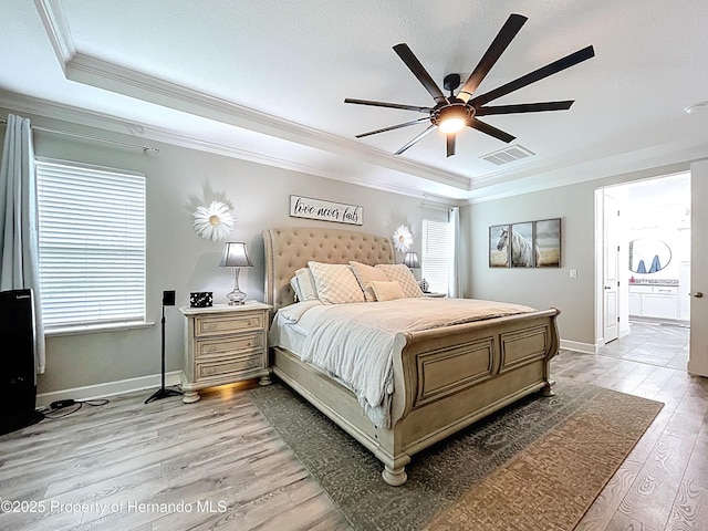 bedroom with a tray ceiling, crown molding, visible vents, light wood-style flooring, and baseboards