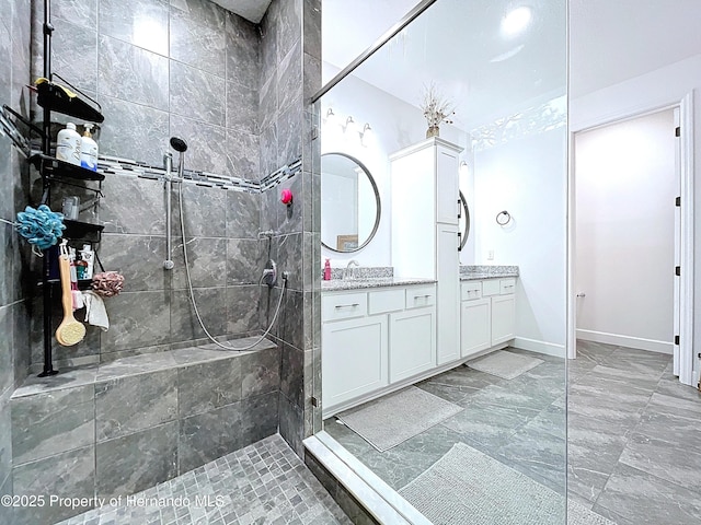 bathroom featuring vanity, baseboards, and a walk in shower