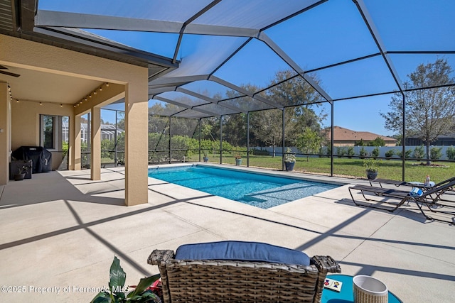 outdoor pool with glass enclosure, a lawn, and a patio area