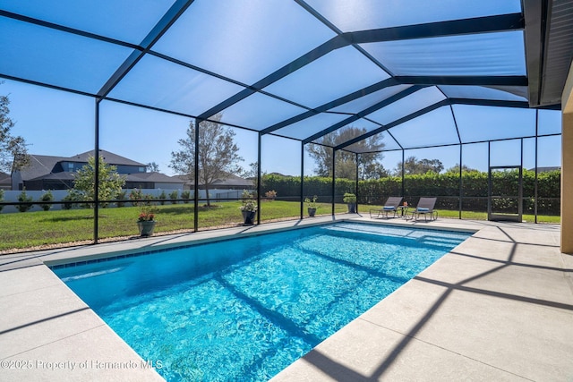 outdoor pool featuring a patio area, glass enclosure, and a yard