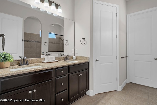 full bathroom featuring double vanity, tile patterned flooring, a sink, and tiled shower