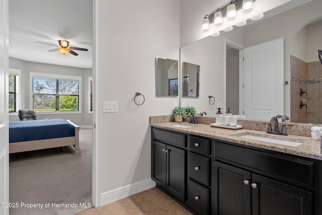 ensuite bathroom featuring baseboards, double vanity, a sink, and tile patterned floors