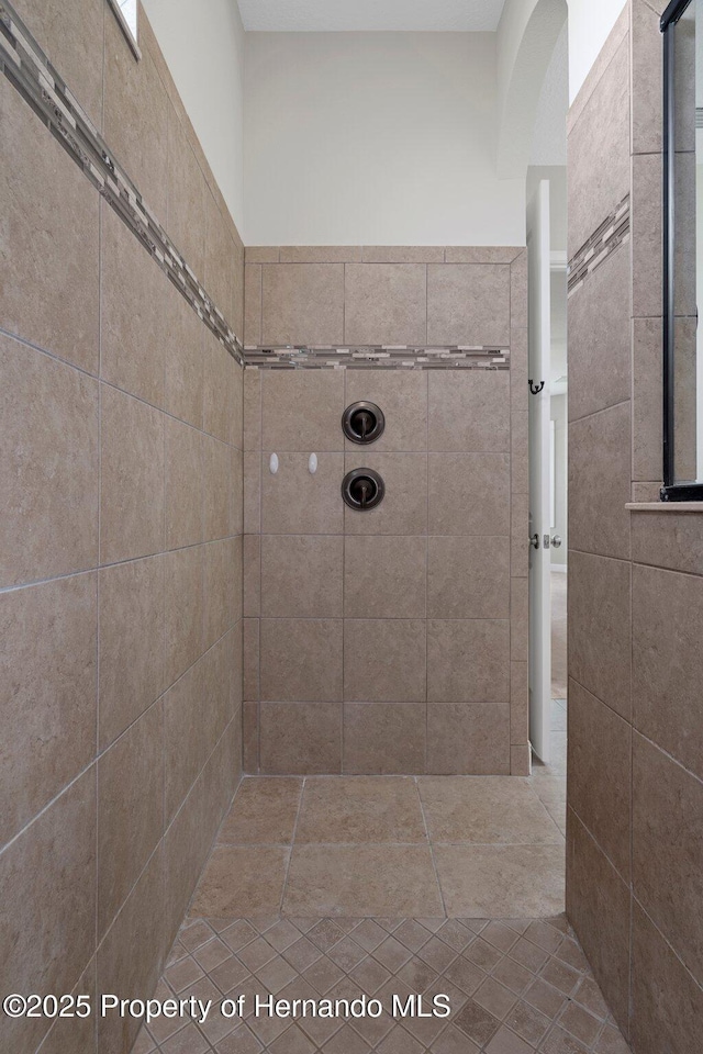 bathroom featuring tiled shower and tile walls