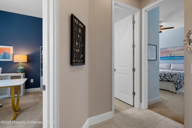 hallway featuring carpet, baseboards, and tile patterned floors