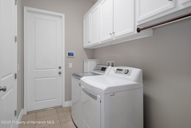 laundry room featuring light tile patterned floors, washer and clothes dryer, cabinet space, and baseboards