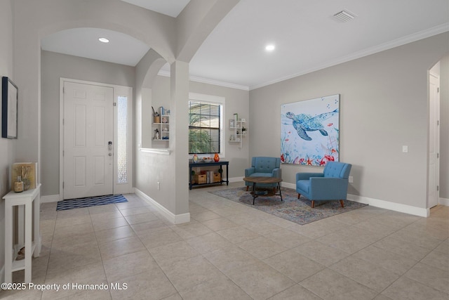 entrance foyer with ornamental molding, arched walkways, light tile patterned flooring, and baseboards