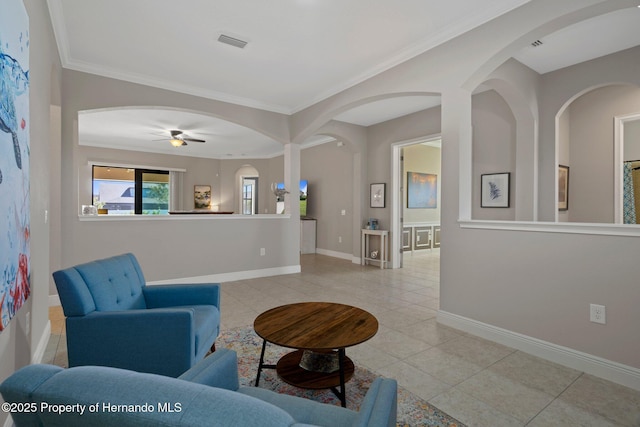 living room with light tile patterned floors, visible vents, ornamental molding, a ceiling fan, and baseboards