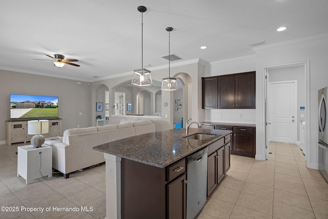 kitchen featuring arched walkways, a sink, dark brown cabinets, appliances with stainless steel finishes, and dark stone countertops