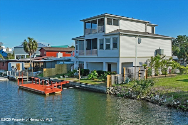 rear view of property with a sunroom, a water view, and fence