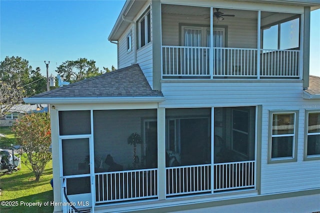 view of side of property featuring a sunroom, a ceiling fan, and roof with shingles