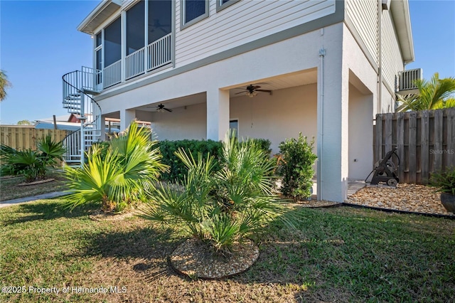 view of home's exterior featuring a lawn, ceiling fan, stairway, fence, and stucco siding