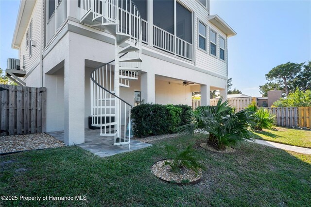 back of property with stucco siding, stairs, fence, and a yard