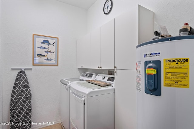 clothes washing area featuring water heater, a textured wall, washing machine and clothes dryer, and cabinet space