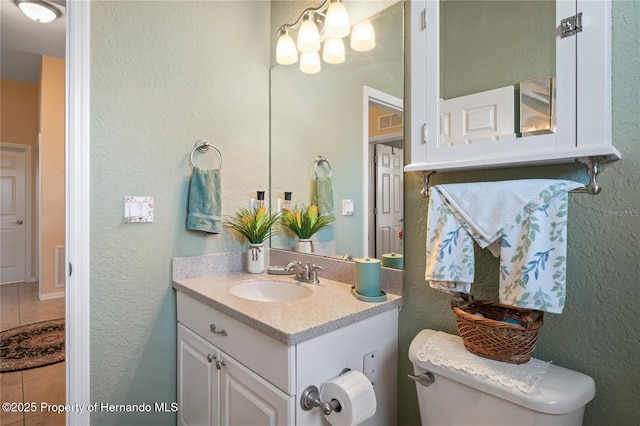 half bath featuring toilet, a textured wall, visible vents, and vanity