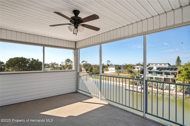 unfurnished sunroom with a water view and a ceiling fan