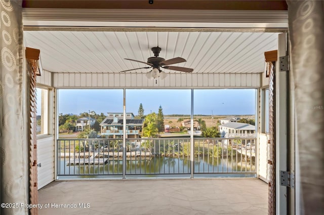 unfurnished sunroom featuring ceiling fan, a water view, and a healthy amount of sunlight