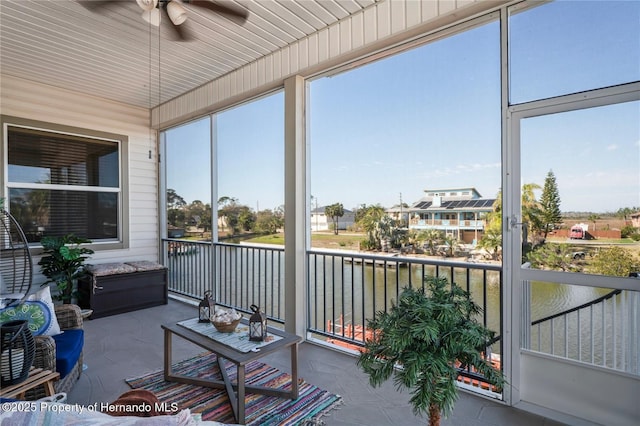 sunroom featuring a ceiling fan and a water view