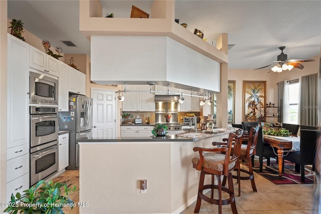 kitchen featuring stainless steel appliances, a peninsula, visible vents, white cabinetry, and dark countertops