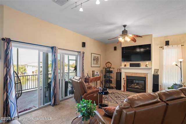 carpeted living room featuring a ceiling fan, a tile fireplace, visible vents, and rail lighting