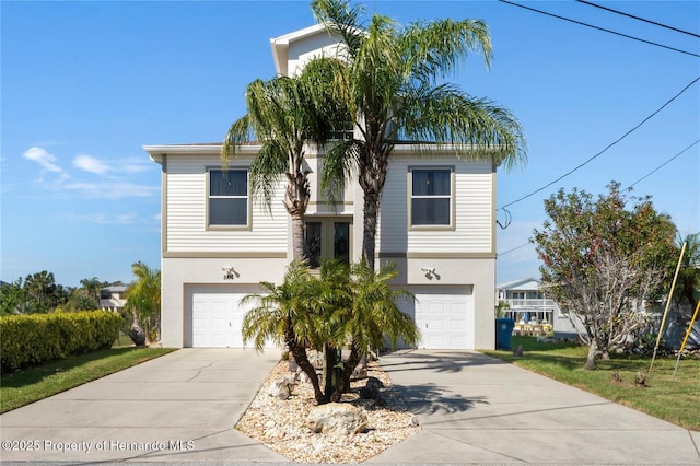 coastal home featuring a garage, driveway, and stucco siding