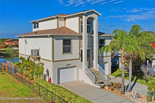 view of front of house featuring an attached garage, cooling unit, a shingled roof, fence, and stucco siding