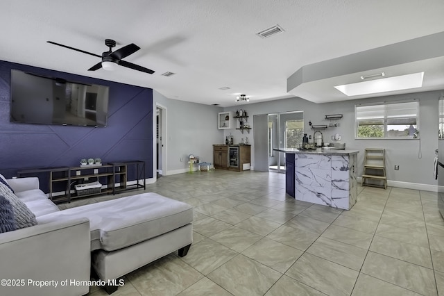 living area with a ceiling fan, visible vents, and baseboards