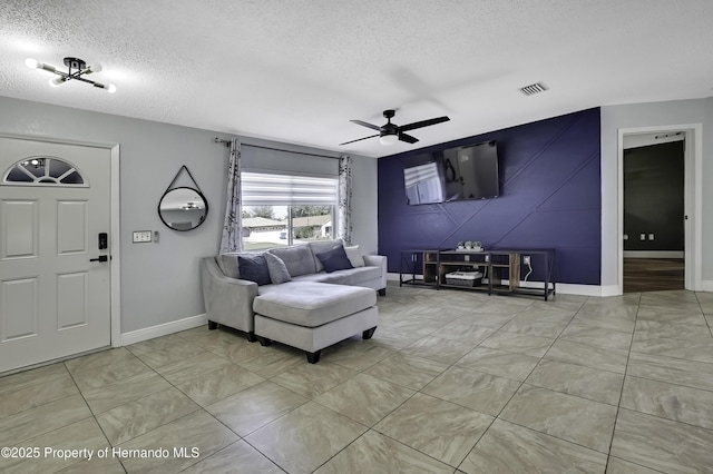 living area featuring visible vents, ceiling fan, a textured ceiling, and baseboards