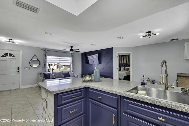 kitchen featuring open floor plan, visible vents, a sink, and blue cabinetry