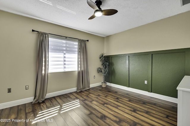 spare room featuring visible vents, a ceiling fan, a textured ceiling, wood finished floors, and baseboards