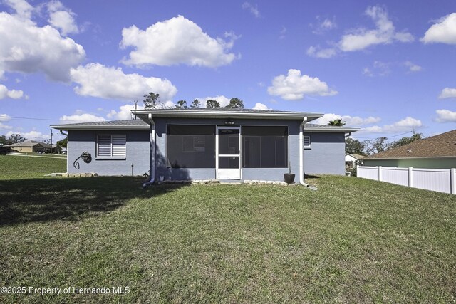 rear view of property with a sunroom, a yard, and fence