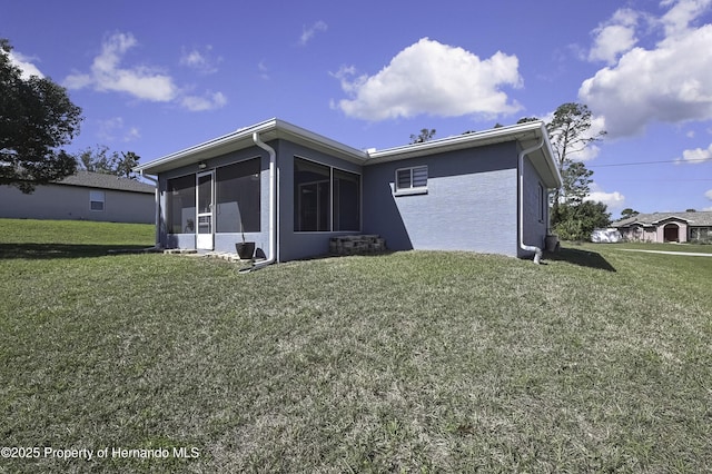 back of property featuring a yard, a sunroom, and stucco siding