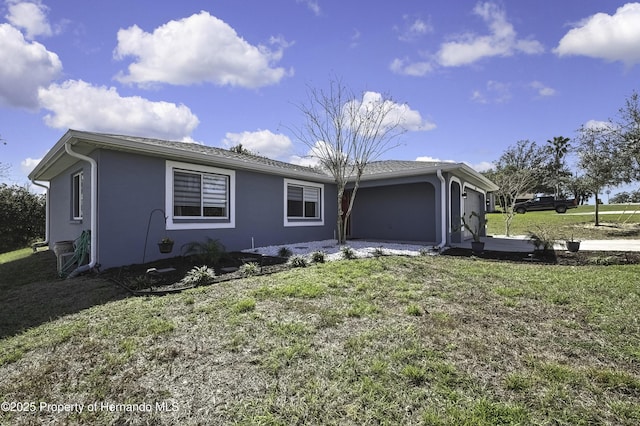 view of front of property featuring an attached garage, a front lawn, and stucco siding