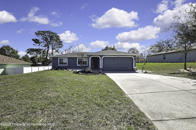 ranch-style home featuring an attached garage, fence, concrete driveway, stucco siding, and a front yard