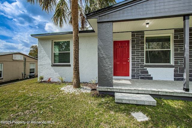 property entrance with a yard, central AC, and stucco siding