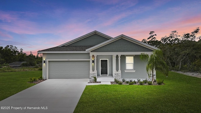 craftsman house featuring roof with shingles, stucco siding, a garage, driveway, and a front lawn