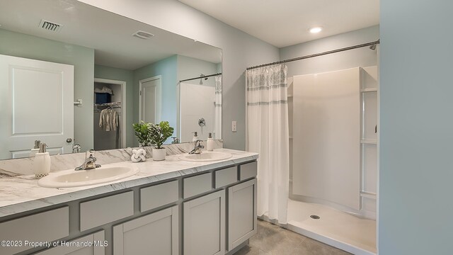 full bath featuring double vanity, a stall shower, a sink, and visible vents