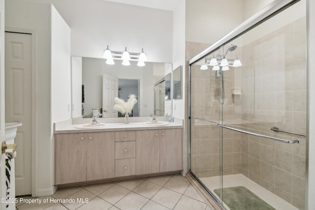 bathroom featuring a stall shower, tile patterned flooring, a sink, and double vanity