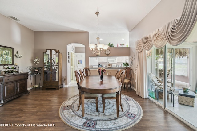 dining area with arched walkways, dark wood finished floors, visible vents, a chandelier, and baseboards