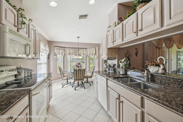 kitchen with light tile patterned floors, visible vents, vaulted ceiling, a sink, and white appliances