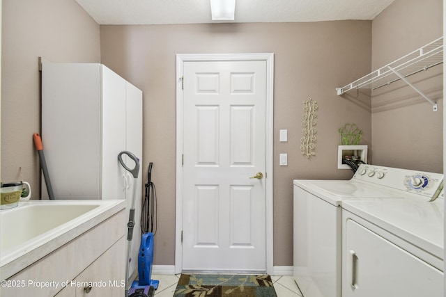 laundry area with light tile patterned floors, separate washer and dryer, cabinet space, and baseboards