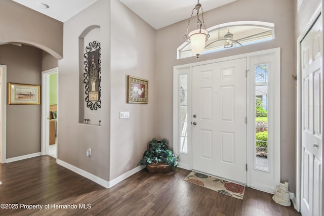 entryway with baseboards, dark wood finished floors, and arched walkways