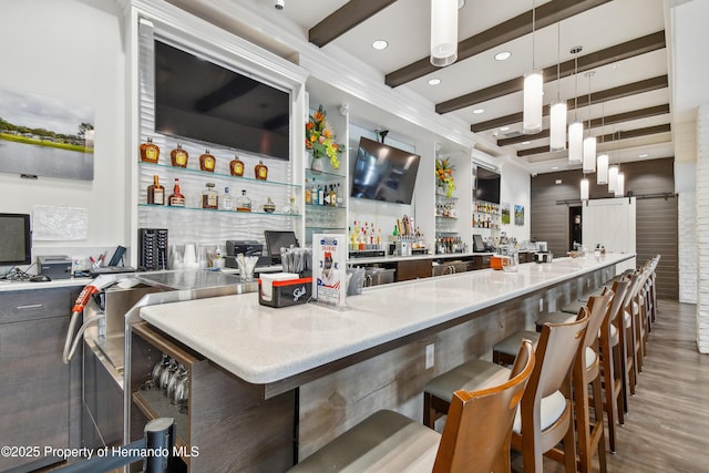 kitchen featuring pendant lighting, wood finished floors, modern cabinets, beamed ceiling, and a kitchen breakfast bar