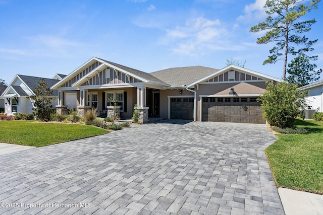 craftsman inspired home featuring a garage, a porch, decorative driveway, a front lawn, and board and batten siding