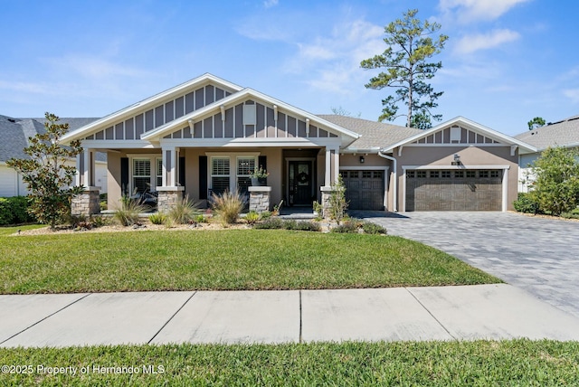 craftsman house featuring an attached garage, decorative driveway, a porch, board and batten siding, and a front yard